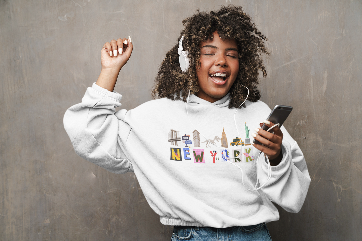 Zay-LA-Vee-Cinched-crop-hoodie-mockup-featuring-a-graphic-design-of-New-York-City-Icons-cheerful-teen-listening-to-music